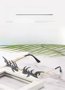 Detail of grey flame-shaped rimless sunglasses with gold metal temples on marble