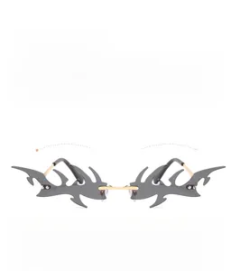 Detail of rimless punk sunglasses with flame-cut grey lenses and gold metal nose bridge