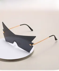 Macro shot of bat-wing rimless sunglasses with gold temples on a white platform