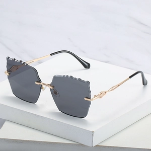 Frameless oversized sunglasses with grey wavy lenses and gold hollowed metal temples