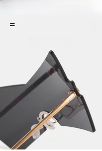 Detail of oversized rimless sunglasses showing golden metal hinges and gradient lenses