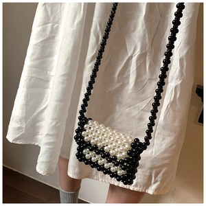 Detail of handmade woven mini pearl crossbody bag with black and white contrast stripes