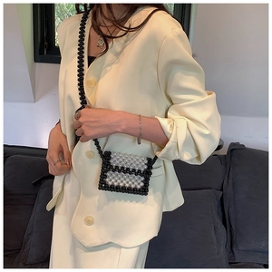 Close-up of handmade black and white pearl beaded crossbody bag with woven strap
