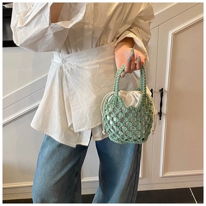 Close-up of light green woven cotton rope bucket bag with a white drawstring inner pouch