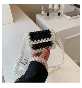 Macro detail of hand-woven black and white beaded mini bag with pearls and crossbody strap