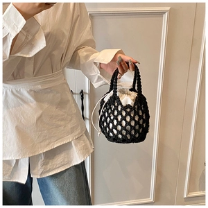 Detail of hand-woven black cotton rope bucket bag with a white canvas drawstring pouch