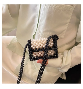 Detail of handmade black and white beaded mini bag showing weaving texture and crossbody strap