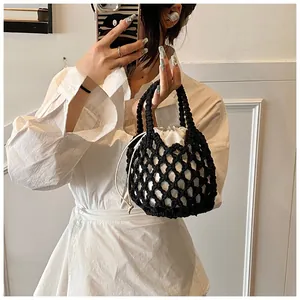 Detail of hand-woven black cotton mesh handbag with white drawstring lining bag