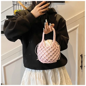 Close-up of pink woven cotton handbag with a white drawstring lining and hollow lattice design