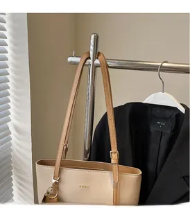 Detail of beige tote bag showing brown straps and WWTU lettering on textured faux leather