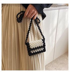 Detail of handmade beaded mini bag featuring black and white woven pattern and strap