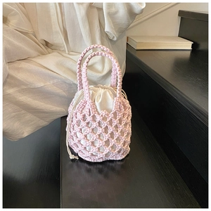 Detail of pink hand-woven cotton bucket bag featuring diamond patterns and white satin drawstring
