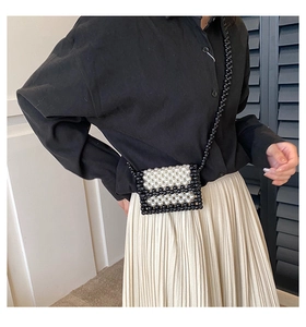 Handmade mini pearl crossbody bag with black and white woven pattern worn by a model