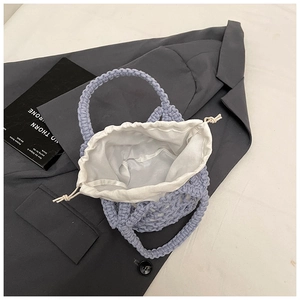 Detailed texture of purple hand-woven cotton rope handbag with white drawstring liner