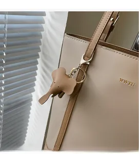 Detail of elephant-shaped leather bag charm in khaki with gold metal hardware