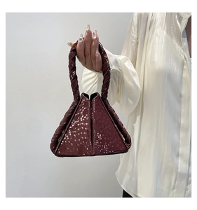 Detailed macro of burgundy snake-embossed mini handbag with braided handle texture