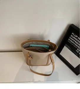 Spacious interior of a beige and brown tote bag showing capacity with a tablet