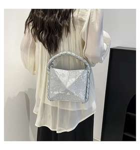Detail of silver snake skin texture and woven handle on a minimalist shoulder bag