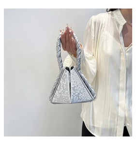 Close-up of silver geometric handbag with snakeskin texture and woven handle