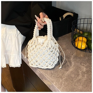Detailed view of white woven cotton rope handbag with hollow mesh and drawstring lining
