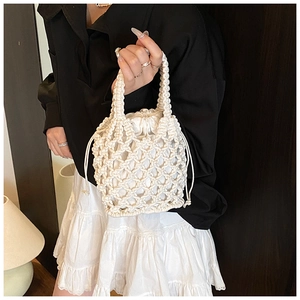 Macro detail of white macrame hollow weave handbag with drawstring cotton lining