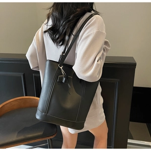 Close-up of black bucket bag featuring WWTU lettering and a stylish bow pendant detail