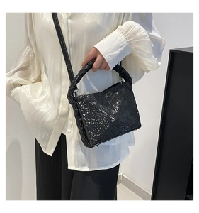 Detail of black python pattern handbag featuring a chunky braided top handle and flap
