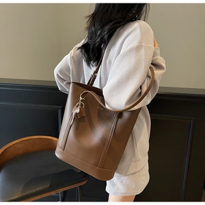 Detail of dark brown leather tote bag with elephant charm and shoulder strap