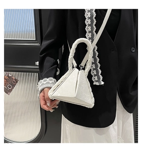 Detail of white triangular handbag with snakeskin texture and twisted handle on model