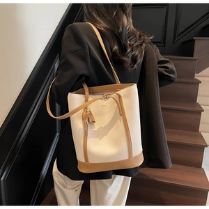 Detail of minimalist cream bucket bag with brown leather trim and cute elephant charm
