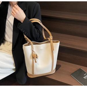 Detail of a cream and brown tote bag featuring a WWTU logo and leather dog charm