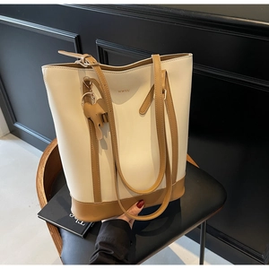 Detail of two-tone tote bag in cream and camel with gold WWTU logo and elephant charm