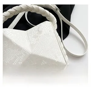 Detailed close-up of white crossbody bag with faux snakeskin texture and braided handle