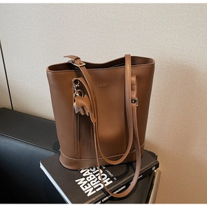 Detail of brown leather tote bag with letter engraving and cute elephant charm