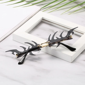 Frameless flame-shaped punk sunglasses with grey lenses and gold metal temples on marble