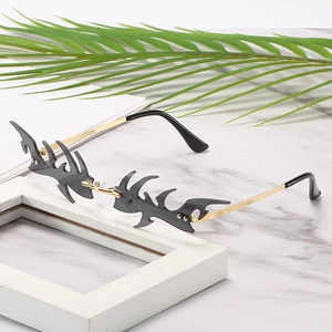 Frameless flame-shaped sunglasses with gray lenses and gold metal frames on marble background