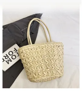Detail view of woven straw tote bag with textured diamond pattern on white fabric