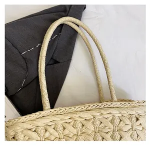 Detailed close-up of woven shoulder strap and reinforced edge on beige straw tote bag