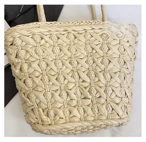 Close-up of handmade straw tote bag featuring detailed hollow floral woven patterns
