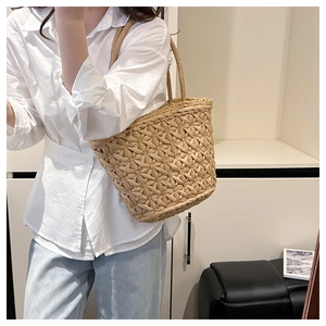 Close-up of a handmade straw woven tote bag featuring a diamond mesh texture and round handle