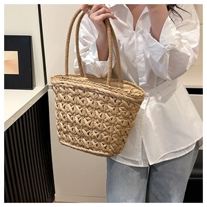 Detail of hand-woven straw tote bag showing intricate honeycomb texture and sturdy handles