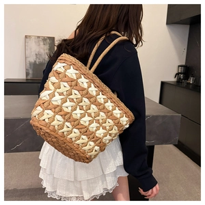 Detail of hand-woven straw tote bag with geometric diamond pattern and shoulder straps