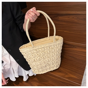 Close-up of beige woven straw tote bag featuring intricate cross-pattern stitch details