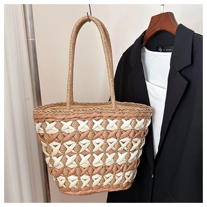 Macro detail of dual-tone straw woven tote bag featuring diamond pattern and round handles