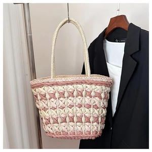 Detail of hand-woven straw tote bag with pink and cream diamond pattern texture