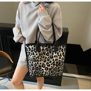 Detail of grey leopard print canvas tote bag with black straps on a female model