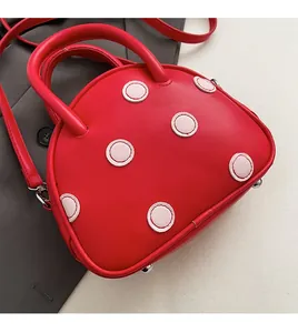 Vue détaillée du sac à pois rouges avec rivets de protection et bandoulière réglable