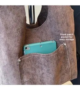 Detail of corduroy tote bag front pocket with a green tablet showing storage capacity