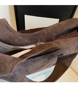 Macro shot of smooth metal zipper and textured brown corduroy fabric on tote bag