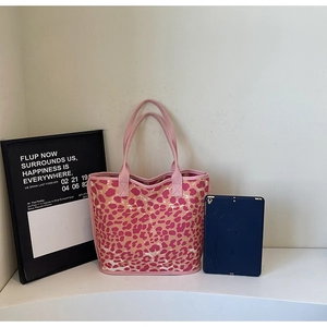 Detailed shot of pink and orange leopard print canvas tote bag on a white surface
